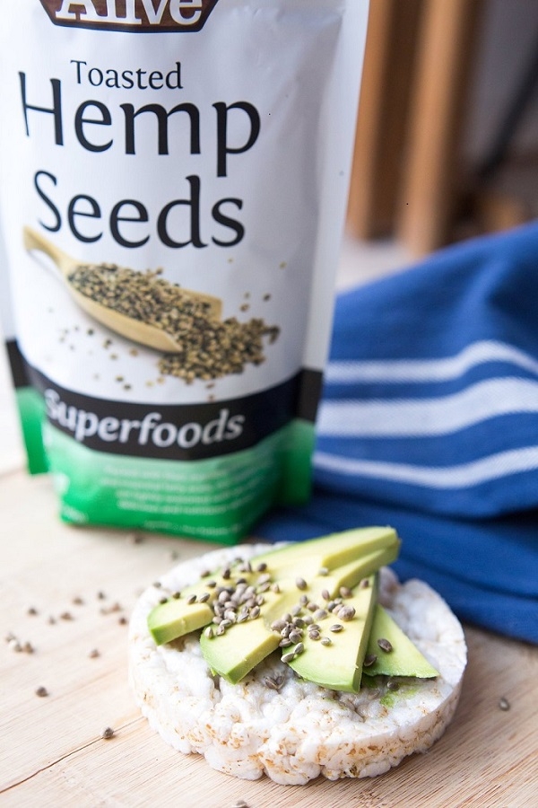 Toasted_Hemp_Seeds_-_Sprinkled_on_rice_cake_with_avocados_on_wood_florr_with_blue_white_cloth_...jpg